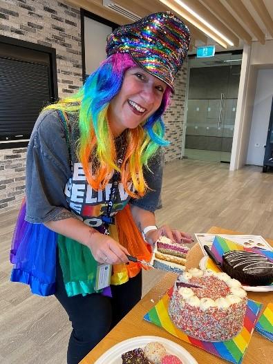 Photograph of Ms Hannah Venn-Brown, Co-chair of Services Australia’s Rainbow Roundtable, cutting a rainbow cake to celebrate Mardi Gras.