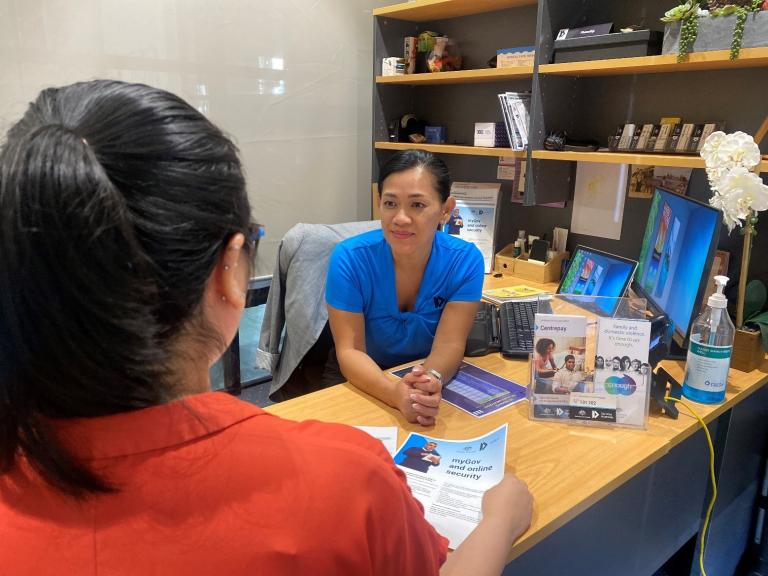 A photograph of two women conversing over a work desk.