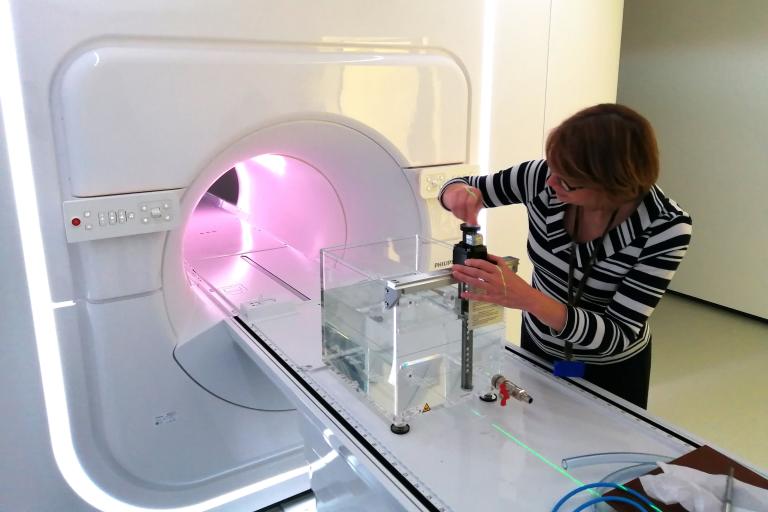 ACDS Director Rhonda Brown shown in front of a magnetic resonance-guided linear accelerator measuring liquid from a bottle.