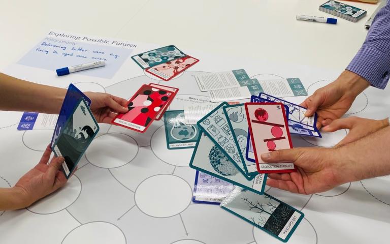 Two sets of hands holding Future primer future cards and arranging on a table. 