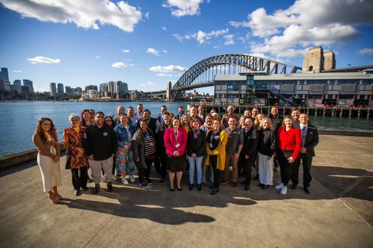 Group of participants, speakers and coaches at the Bulabul leadership gathered on Sydney harbour in front of Sydney Harbour Bridge. 