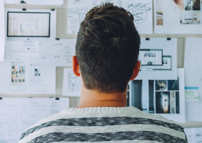 Man standing with back to the viewer, looking at data on a board