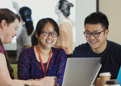 A group of people smiling around a laptop