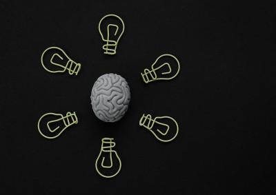 six yellow lightbulbs circled around a cartoon brain against a black background