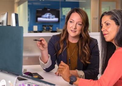 Image of two office workers collaborating on a task at a computer