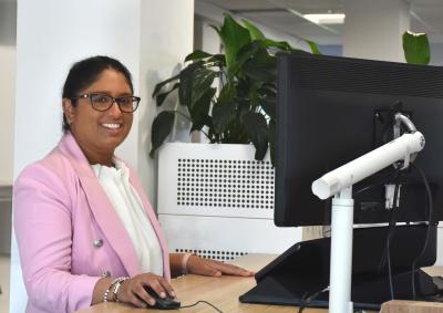 an image of a woman smiling while working in front of a computer in an office