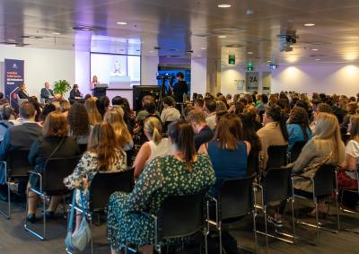 Image of a group of people sitting towards a stage with a panel of people