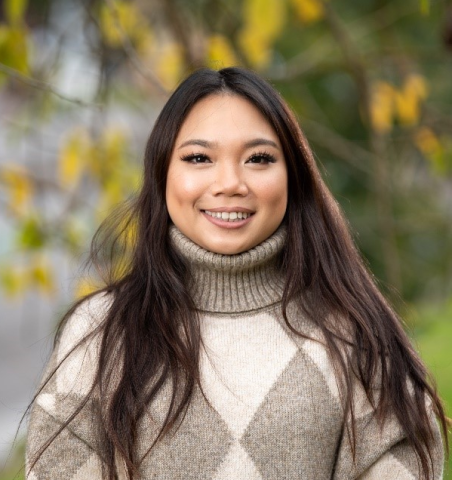 Organ donor recipient Kristy pictured in an outdoor setting in front of a tree with yellow and green leaves, smiling at the camera. 