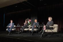 A panel of speakers sitting on a stage in conversation