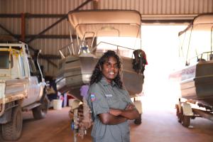 A photo of an Bawinanga Ranger, Grestina Wilson standing in front of a boat